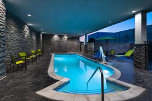 una piscina en un edificio con sillas y mesas en SpringHill Suites by Marriott Austin North, en Austin