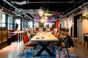 - une salle à manger avec une table, des chaises, des tables et des chaises dans l'établissement Moxy The Hague, à La Haye