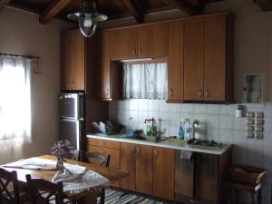 uma cozinha com armários de madeira, uma mesa e um frigorífico em Antonis Stone house em Zárakes