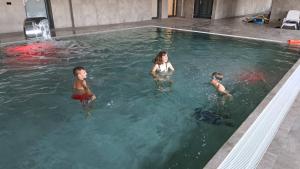 drei Kinder schwimmen im Pool in der Unterkunft Apartament z widokiem Dziwnów & Spa, in Dziwnów