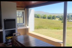 um quarto com uma grande janela com uma mesa e uma vista em Lalamanzi Trout Cottage - Solar Powered em Underberg