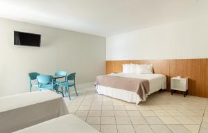 a hotel room with a bed and a table and chairs at Ilha Porchat Hotel in São Vicente