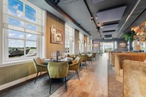 un restaurant avec des tables, des chaises et des fenêtres dans l'établissement Hotel Maassluis, à Maassluis