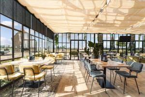 un restaurant avec des tables, des chaises et des fenêtres dans l'établissement Hotel Maassluis, à Maassluis