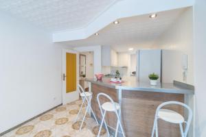 une cuisine avec des murs blancs et un comptoir avec des tabourets dans l'établissement Basic Comfort Apartment Port Emporda 0195, à Empuriabrava