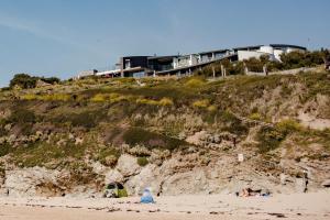 uma casa no topo de uma colina ao lado de uma praia em Scarlet Hotel em Mawgan Porth