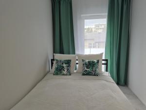 um quarto com uma cama com cortinas verdes e uma janela em Apartament Zacisze 4 em Piaseczno