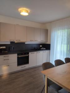 uma cozinha com armários brancos, uma mesa e uma sala de jantar em Hotel & Appartements Nice Garni em Ichenhausen