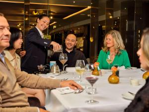 een groep mensen die rond een tafel in een restaurant zitten bij Sofitel Legend The Grand Amsterdam in Amsterdam