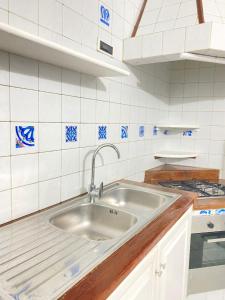 cocina con fregadero y pared de azulejos blancos en Tiffany Holiday Home en Isquia