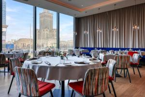 comedor con mesas y sillas y ventanas grandes en Warsaw Presidential Hotel, en Varsovia