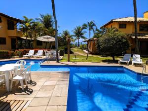 una piscina con tavolo e sedie accanto a una casa di Residence Maria Vittoria Praia Arraial a Arraial d'Ajuda