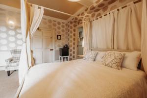 1 dormitorio con 1 cama blanca grande con cortinas en Old Orleton Inn, en Wellington