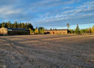 um campo de terra vazio com edifícios ao fundo em Ofvansjö Gård , Enkel stuga för övernattning på ett fd militärområde em Sandviken