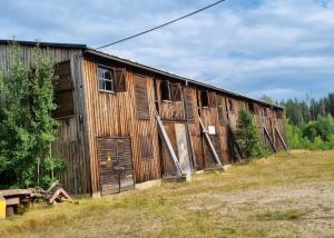 um velho edifício de madeira sentado num campo em Ofvansjö Gård , Enkel stuga för övernattning på ett fd militärområde em Sandviken