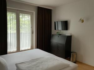 1 dormitorio con 1 cama, TV y ventana en Hotel Berg en Seekirchen Markt