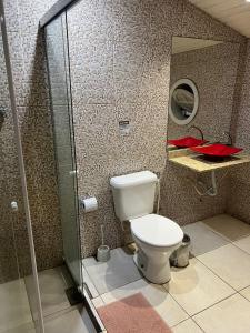 uma casa de banho com um WC e uma cabina de duche em vidro. em Pousada Americas em Búzios