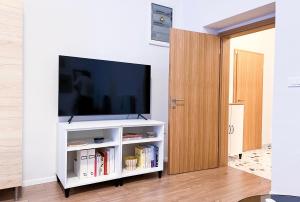 una sala de estar con TV en un centro de entretenimiento blanco en Aumetz square apartment en Idrija