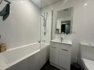 ein weißes Bad mit einer Badewanne, einem Waschbecken und einer Dusche in der Unterkunft Cozy & Spacious 3 Bedroom House Glebe in Sydney