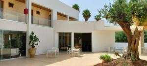 un bâtiment blanc avec des tables, des chaises et un arbre dans l'établissement Baitan Hotel, à Marsala