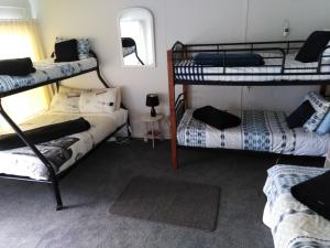 a room with three bunk beds and a mirror at Charmae Guest House in Whanganui