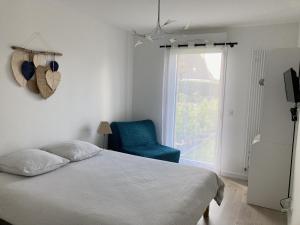 1 dormitorio con cama, silla azul y ventana en TY DOLMEN DU Plages à pied 2 vélos WIFI en Carnac