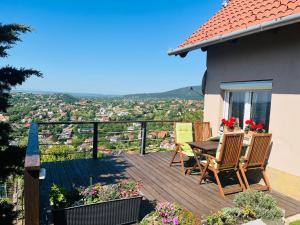 eine Holzterrasse mit einem Tisch und Stühlen auf einem Haus in der Unterkunft Panoráma Vendégház in Pécs