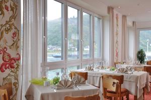 een eetkamer met tafels met witte tafelkleden bij Weinhotel Landsknecht in Sankt Goar