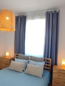 um quarto com cortinas azuis e uma cama com almofadas em Aegina Port Apt 2-Διαμέρισμα στο λιμάνι της Αίγινας 2 em Aegina Town