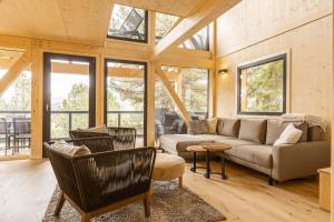 sala de estar con sofá, sillas y ventanas en Naturchalets Turracher Höhe by ALPS RESORTS, en Turracher Höhe