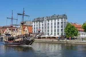 ein Piratenschiff im Wasser neben einem Gebäude in der Unterkunft Chrobry Apartamenty Gdańsk Grodzka 10 in Danzig