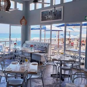 um restaurante com mesas e cadeiras e vista para o oceano em M1 Umdloti Resort em Umdloti