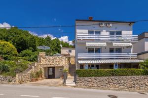 un edificio blanco con una pared de piedra junto a una calle en Guest House Stella, en Dramalj