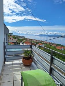 un balcón con una silla verde y vistas al agua en Guest House Stella, en Dramalj