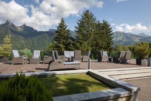 eine Gruppe von Stühlen auf einer Terrasse mit Bergen in der Unterkunft Hôtel de Gruyères in Gruyères