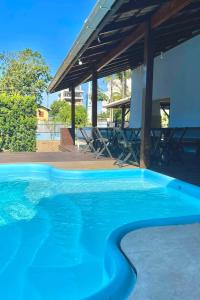 una gran piscina azul frente a una casa en Hangar Pousada en Navegantes