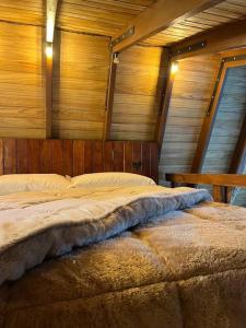 Cama grande en habitación con paredes de madera en Jardim Secreto Chalé Azaléia en Nova Friburgo