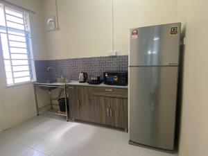 a kitchen with a stainless steel refrigerator in a room at Homestay Rumoh Mok in Jitra