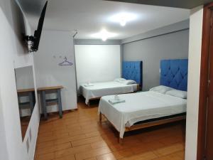 1 dormitorio con 2 camas y mesa en Tumalki rooms en Trujillo