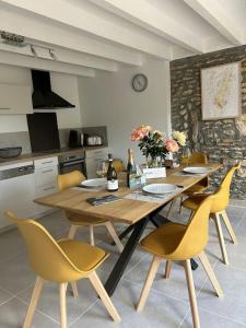 una sala da pranzo con tavolo in legno e sedie gialle di Les Murgers Au coeur des Vignes a Prissé