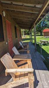 een veranda met 2 houten stoelen en een rode deur bij Strautmali Forest House in Mazirbe