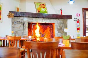 una chimenea en un comedor con mesas y sillas en VELINN Hotel Ninho do Falcão, en Monte Verde