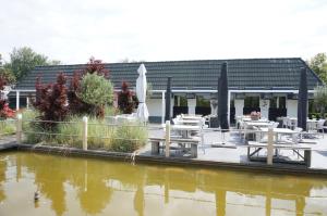 un restaurante con mesas y sombrillas junto a un cuerpo de agua en Kustverhuur, Park Schoneveld, Duinroos 102 en Breskens