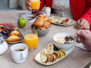 - une table avec des assiettes de produits pour le petit-déjeuner et du jus d'orange dans l'établissement ibis Lausanne Centre, à Lausanne