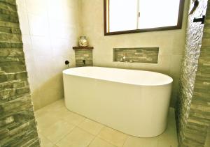 baño con bañera blanca y ventana en Auwas Island Holiday Home en Burnt Pine