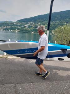 een man die naast een boot op het water loopt bij Dolceresio Lugano Lake B&B in Brusino Arsizio