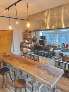 una cocina con una mesa de madera larga en ゲストハウス千倉のおへそ en Chikura