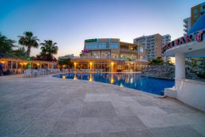 un hôtel avec une piscine en face d'un bâtiment dans l'établissement Caesar Resort - Studio Apartments, à Iskele