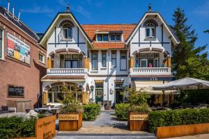 una grande casa bianca con un edificio in mattoni di Dijkstra Hotels a Bergen