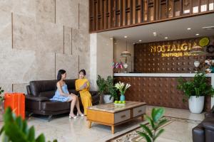 Due donne sedute su un divano nell'atrio di Nostalgia Boutique Hotel a Da Nang